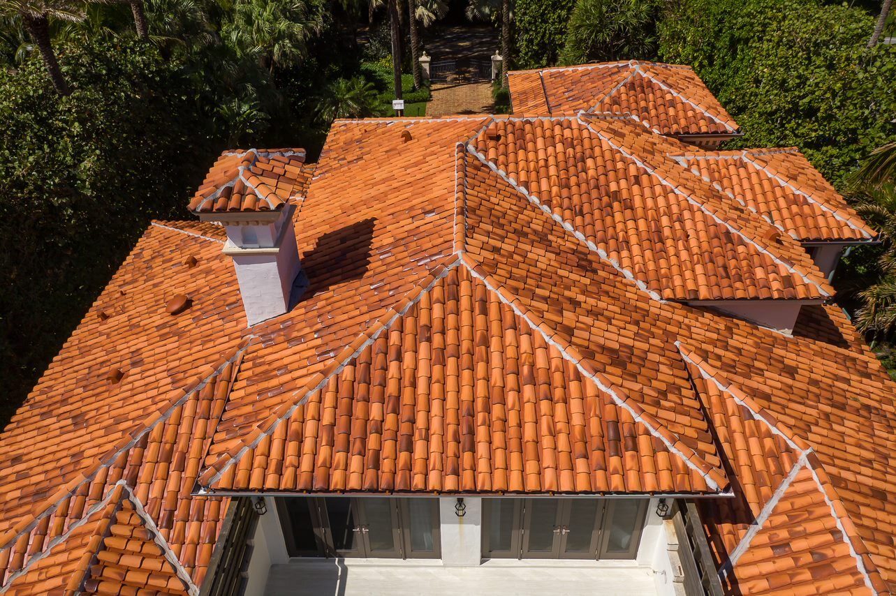 Terracotta ridge tiles and roof planes on a completed coastal tile roof.